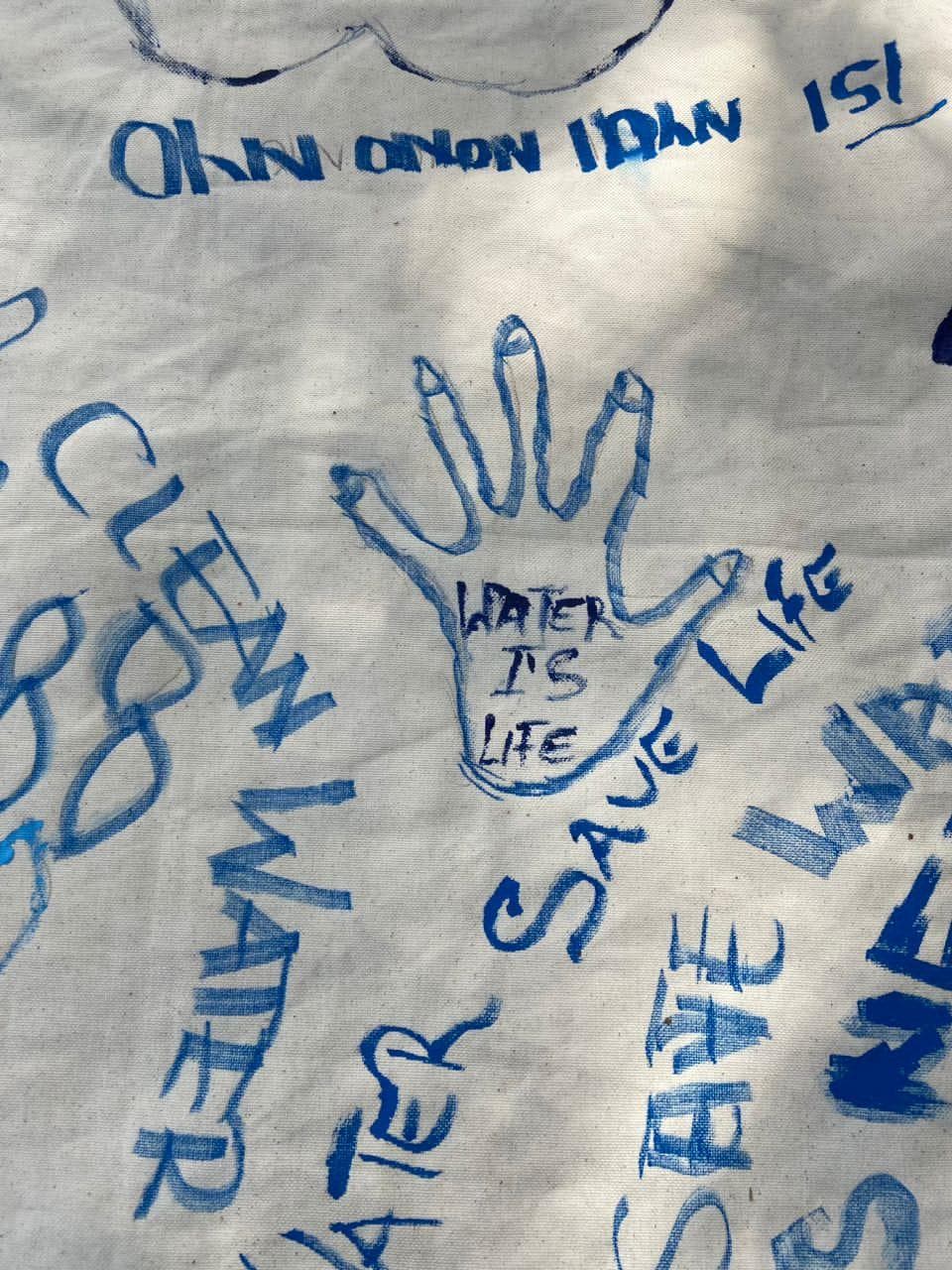 Hand-painted cloth reading 'Water is life' and 'Clean water' from an AYWF campaign